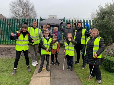 Group of kids and adults in high-vis jackets with litter pickers